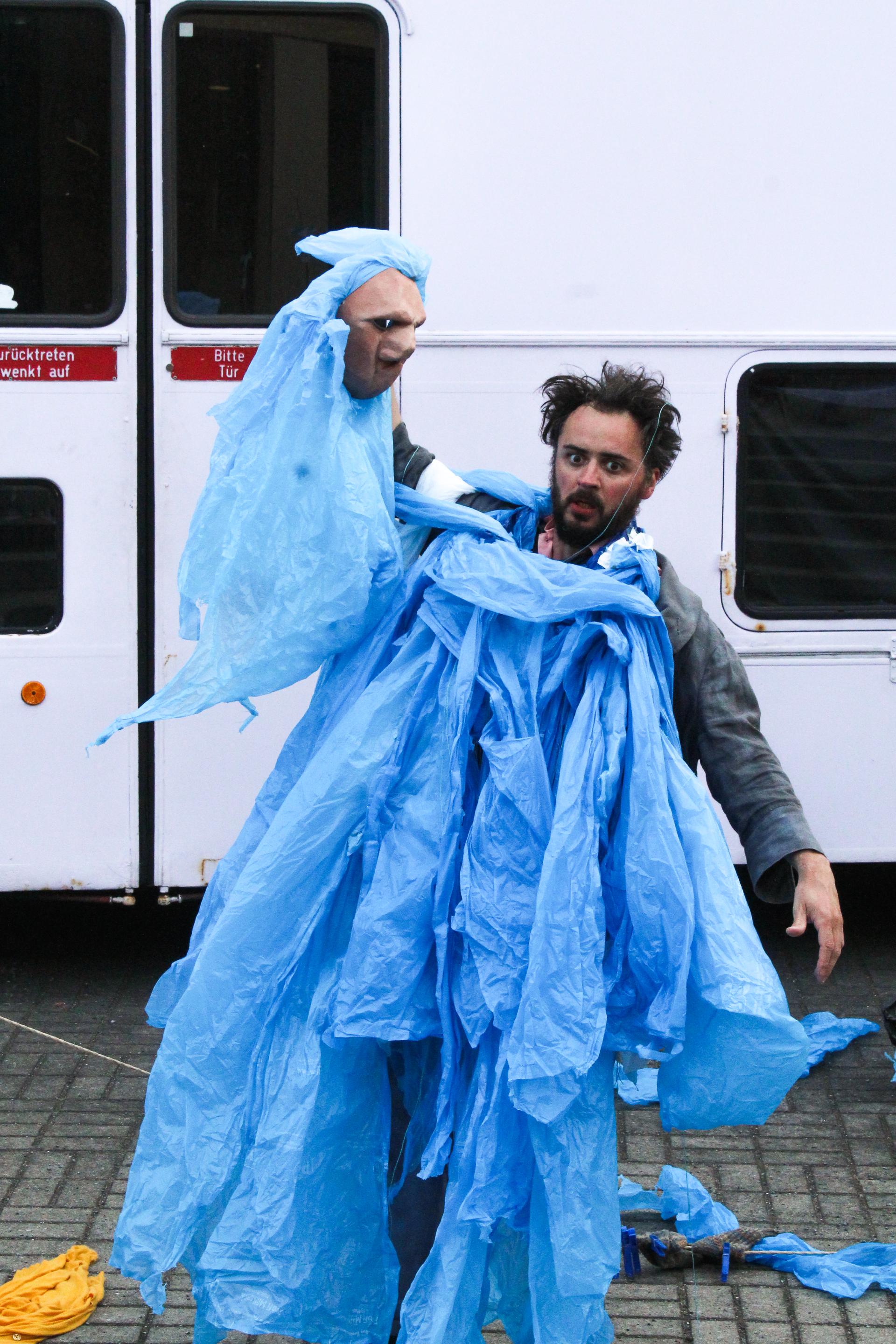 A performer wearing a costume made from blue bin bags