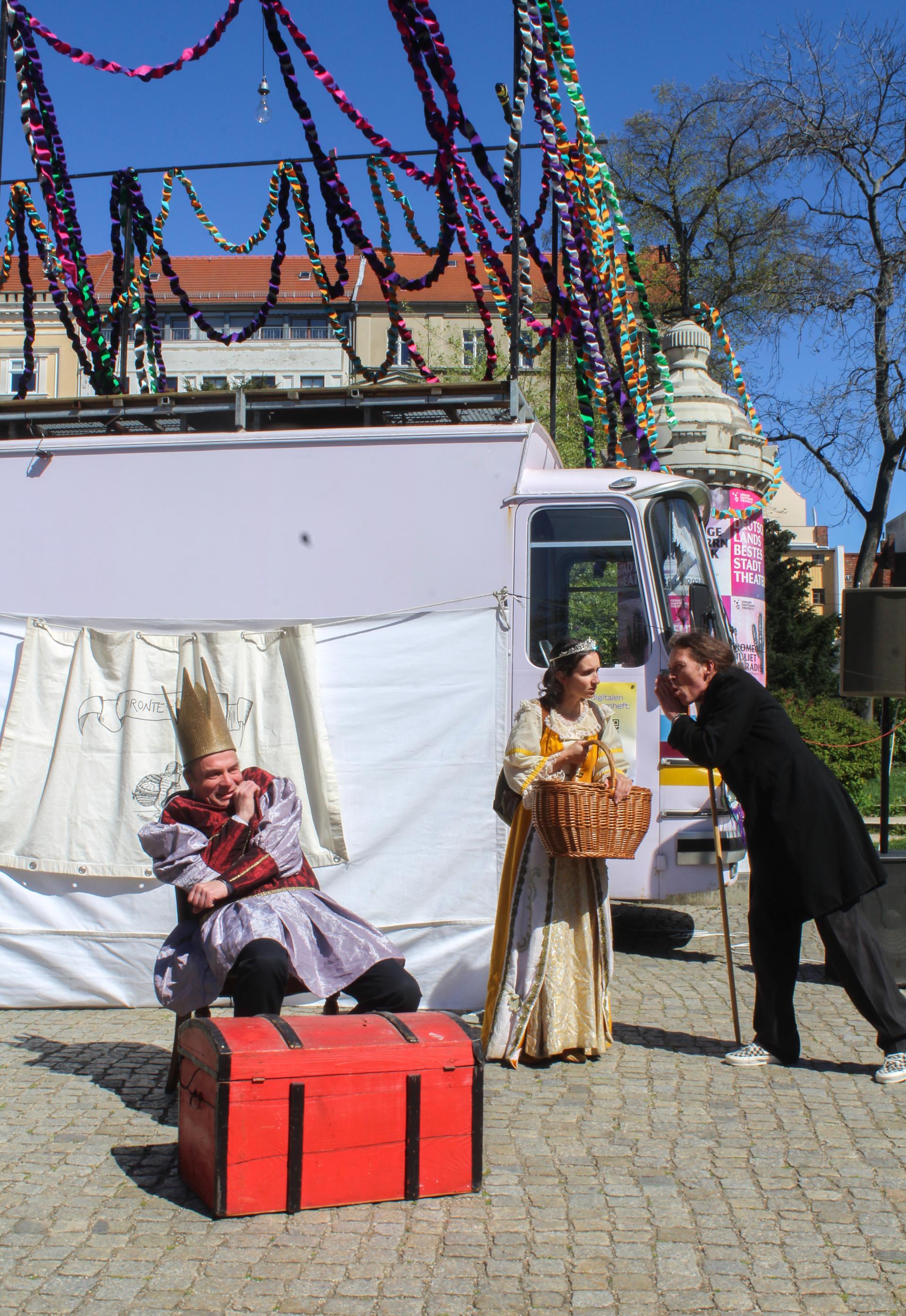 Three performers in medieval costumes in front of a bus