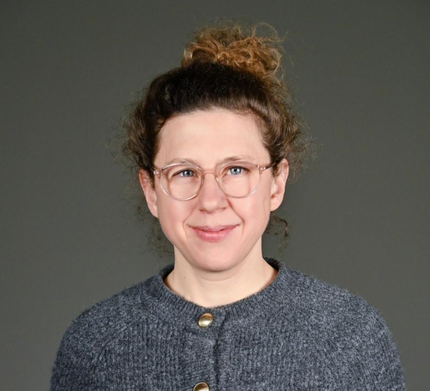 Josephine Bock Portrait of Josephine Bock with curly hair in a bun and gray cardigan, looking frontally into the camera, against a light background