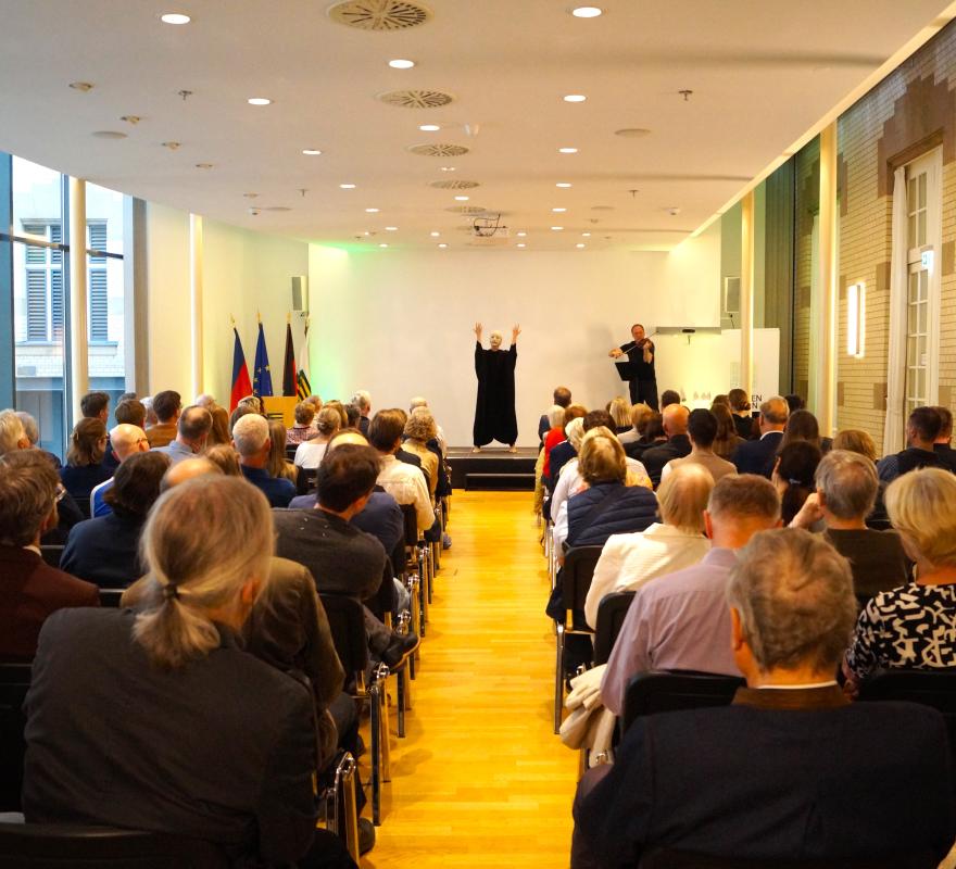 Performerin mit Maske vor großem Publikum in Berlin
